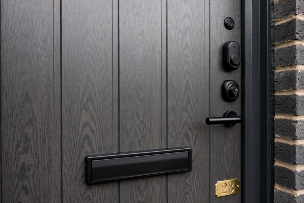 Anthracite grey composite front entrance door with woodgrain finish and black hardware on UK brick home